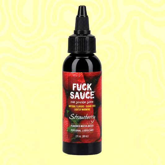 A bottle of Fuck Sauce Strawberry flavored water-based personal lubricant on a pale yellow background with wavy lines. The bottle is black with a red label featuring strawberries and white text.
